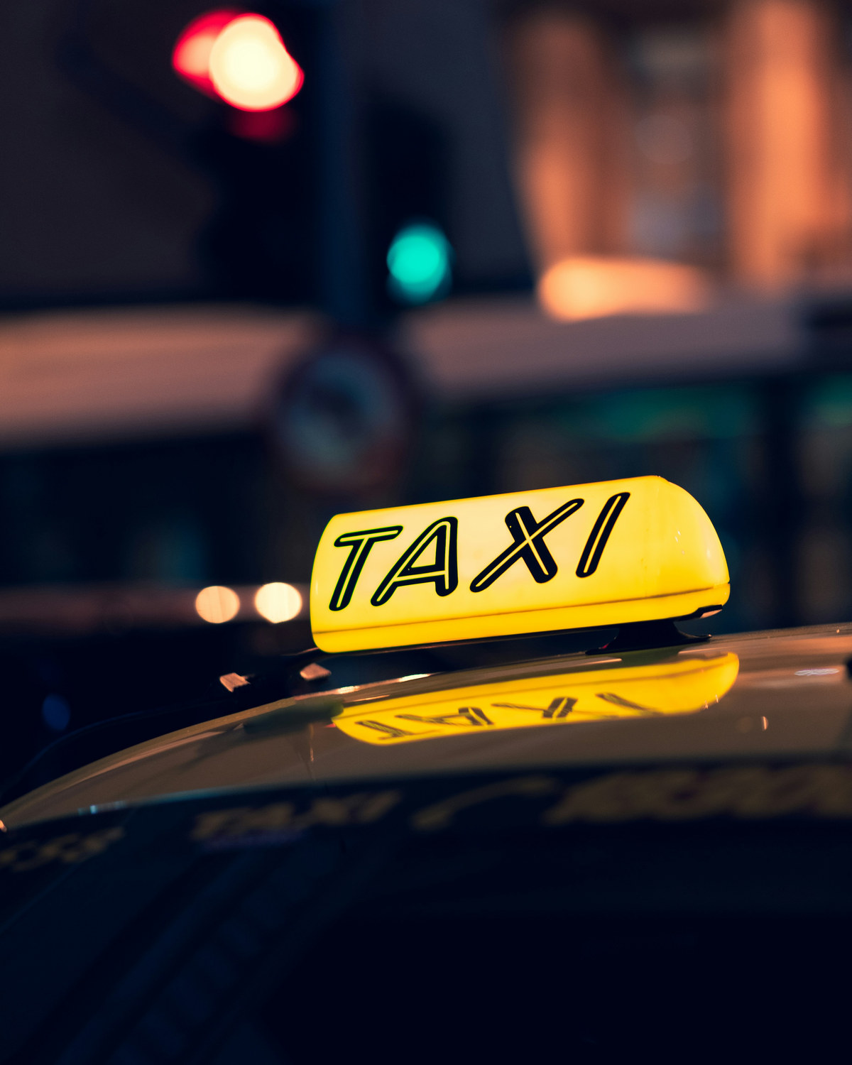 Beleuchteter Taxistand bei Nacht mit einem Leuchtschild mit der Aufschrift Taxi.
